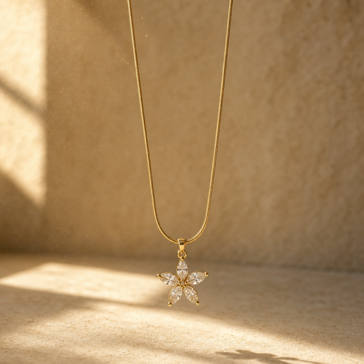 One necklace in yellow-gold-toned metal with a polished finish. It is a single strand of fine, tight snake chain of small gauge, carrying one dominant pendant. The visible chain run is roughly twenty times the pendant's width; no extender chain is visible, and no working clasp is visible as the strand ends extend out of view.