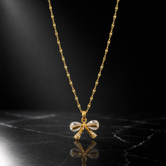 One necklace in yellow gold-tone metal with a polished finish. A single fine strand of flattened, elongated decorative link chain of small gauge carries one dominant bow pendant suspended from a tapered metal bail by a jump ring; the chain ends run off-frame and no clasp, extender or terminal tag is visible, so no working closure can be confirmed. The visible chain run is approximately twenty-five to thirty times the pendant's width.