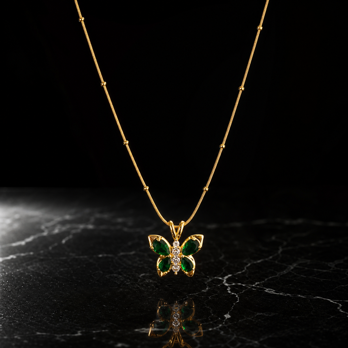 A single pendant necklace in yellow-gold-toned metal with a polished finish. It is one strand of fine snake chain of narrow gauge, interrupted by small round gold bead stations fixed at irregular intervals along the run; the chain exits the frame at both ends, so the full run is partly obscured and no clasp or extender is visible. The visible chain run is roughly twelve to fourteen times the width of the pendant, the largest component.