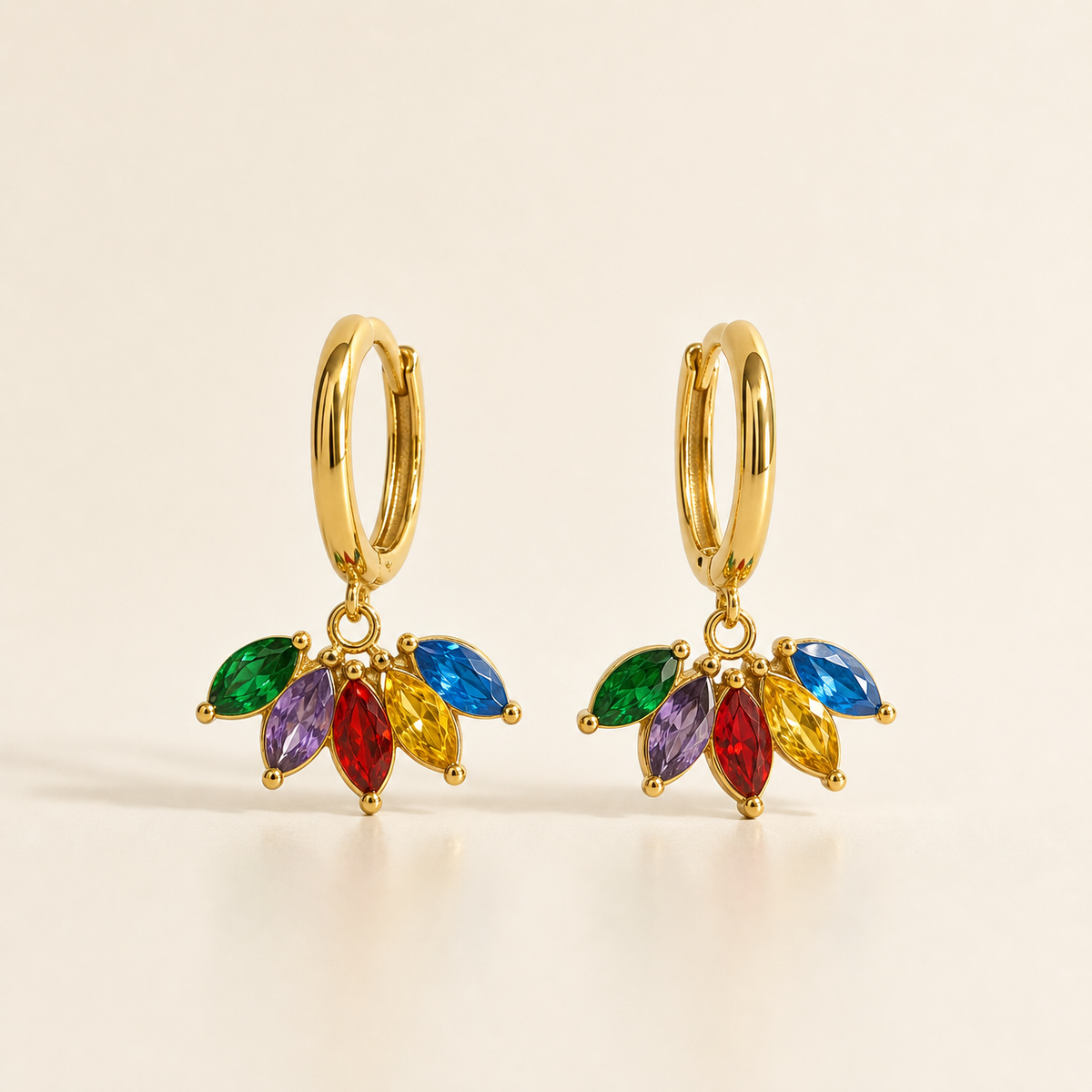 Two earrings, one design: gold-tone metal with polished finish. Each is a small hinged huggie hoop fitting, roughly 12 mm in diameter with a slim gauge, opening at the bottom of the hoop. From the hoop's base hangs a single articulated section: a cluster of five marquise-cut faceted stones in gold-tone prong settings joined to the hoop by a small jump ring. The stones run green, purple, red, yellow and blue, each of similar size and pointed-oval shape. Total drop is about twice the hoop width.