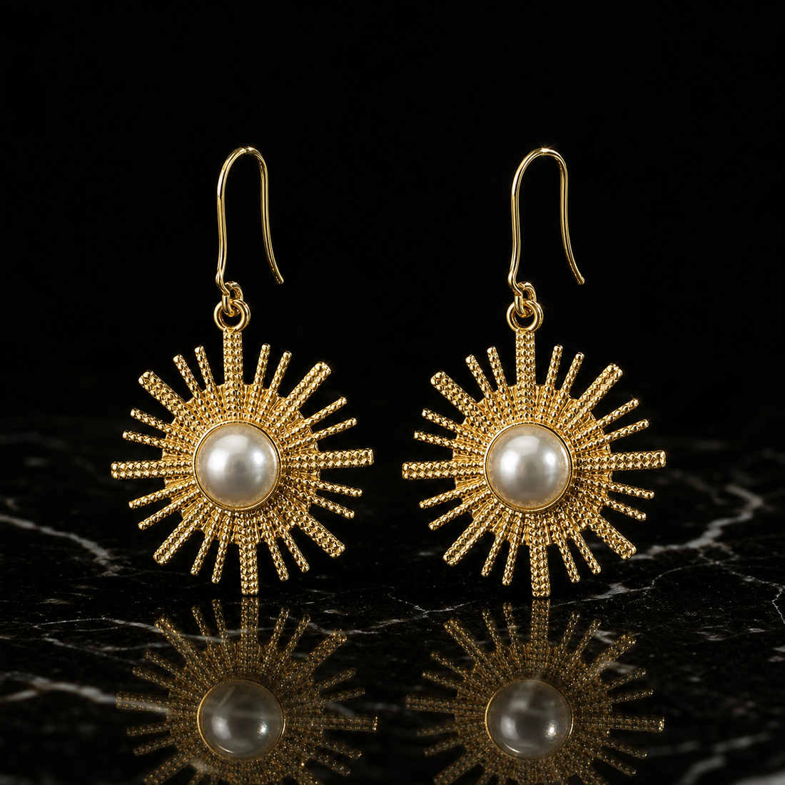 Two earrings of one coordinated design. Gold-tone metal with polished French hook ear wires of moderate length and fine gauge; each hook joins through a small jump ring to a single rigid sunburst drop, giving one hanging section that swings from the fitting. Overall drop is about twice the widest sunburst diameter.