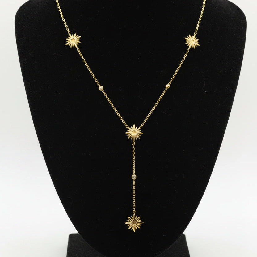 Gold necklace with star-shaped pendants on a dark surface
