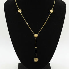 Gold necklace with star-shaped pendants on a dark surface