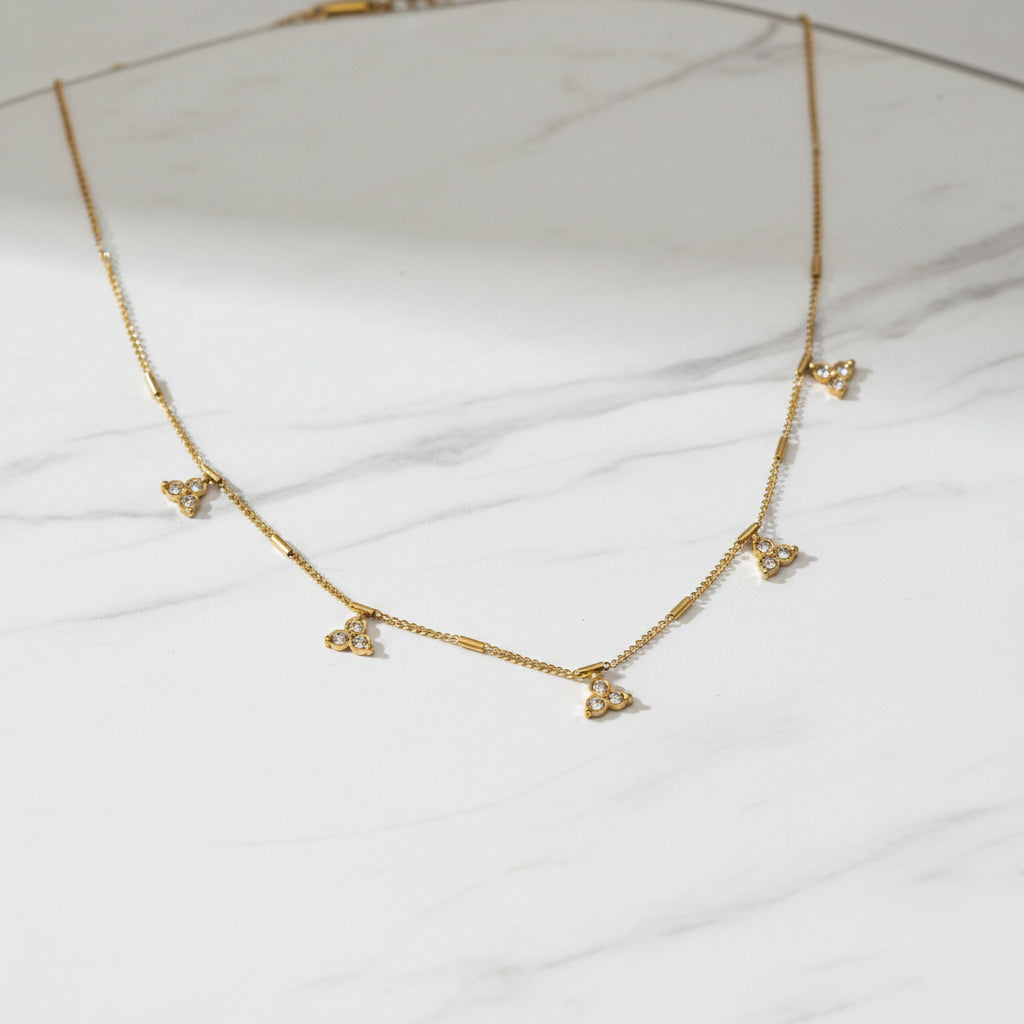 Gold necklace with diamond-like pendants on a black stand