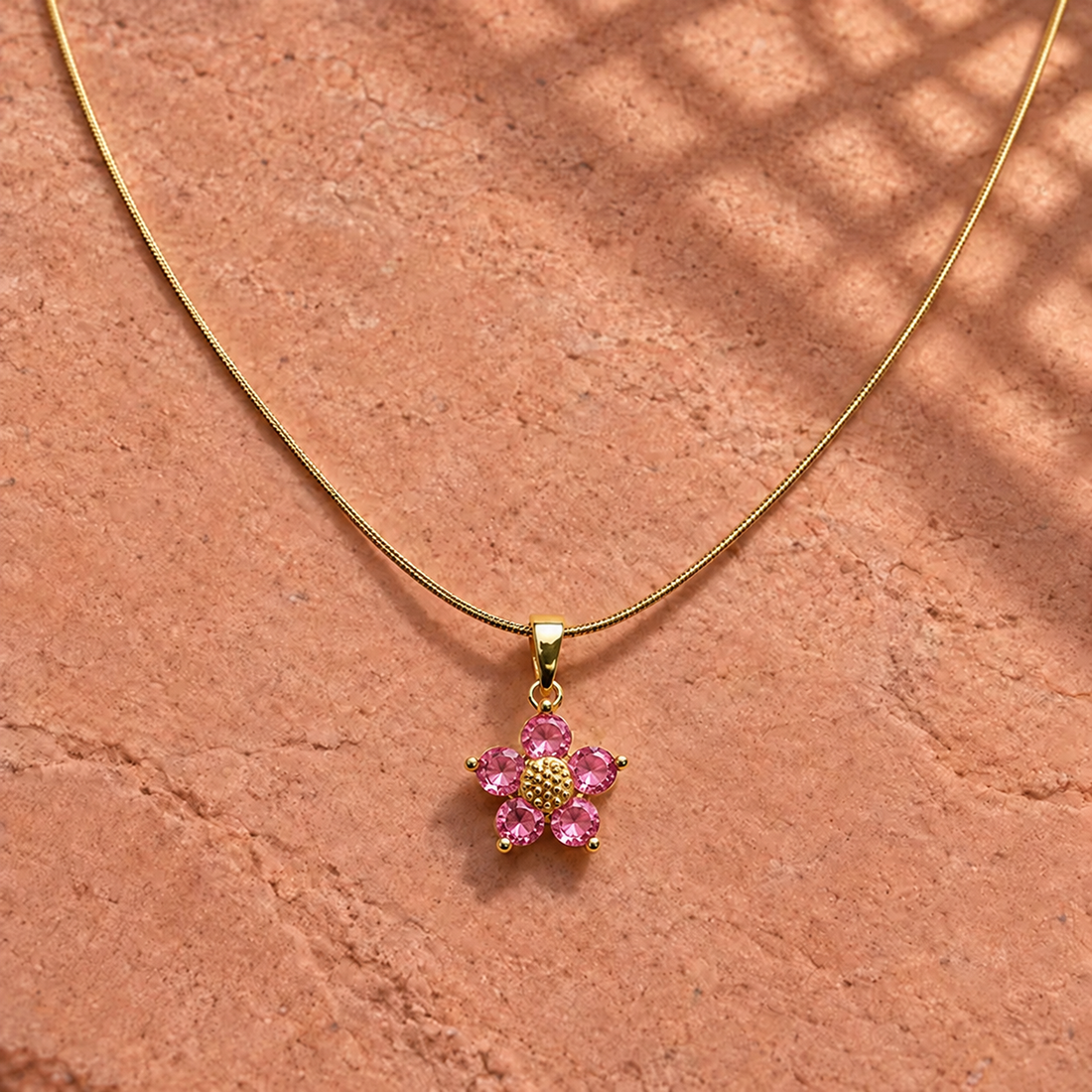 Gold-tone 316L stainless steel pendant necklace with a five-petal flower of pink stones and a gold-tone centre