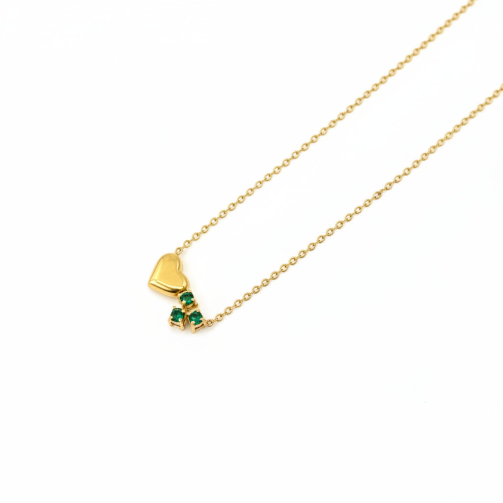 Gold necklace with a heart-shaped pendant on a gray background