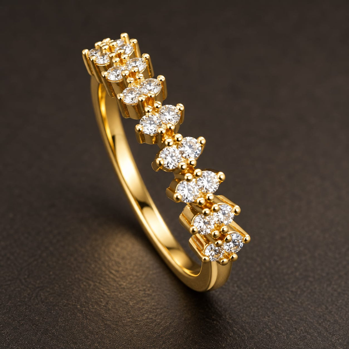 A yellow gold eternity-style ring featuring a row of marquise-cut clear gemstones, photographed on a dark textured background.