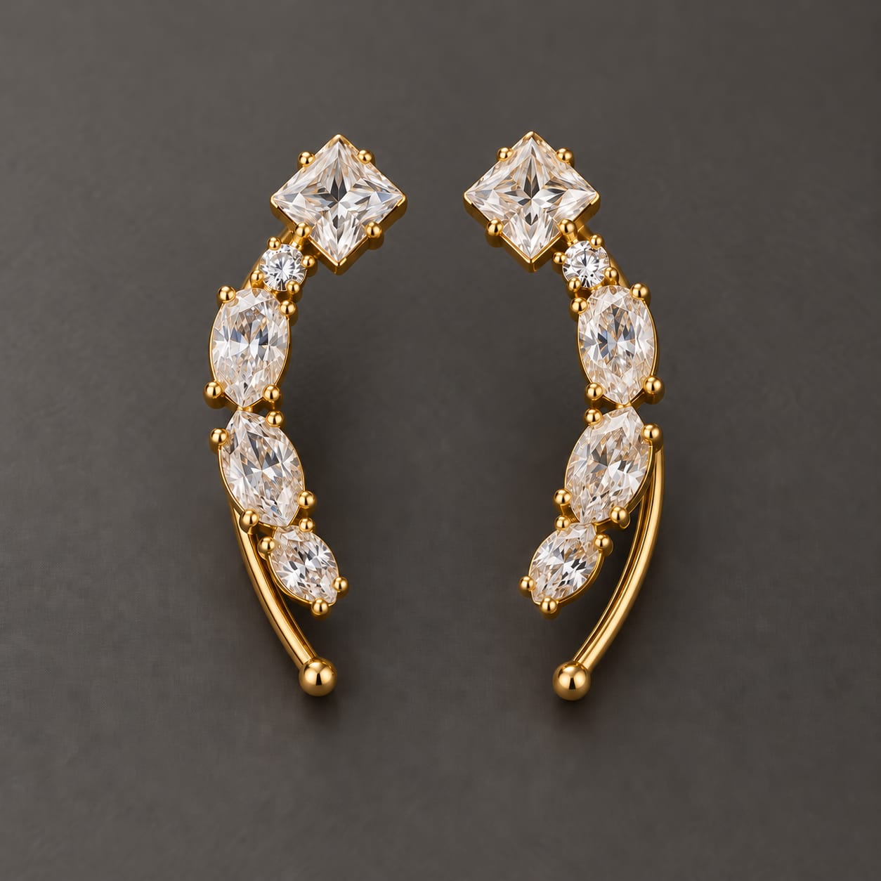 Gold-tone brass climber earrings with a curved row of clear princess and marquise cut stones and a round stone, worn as a pair