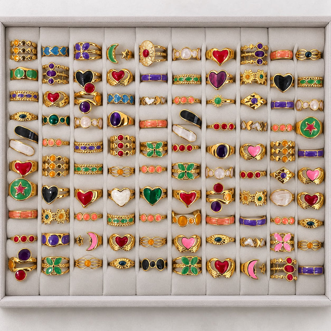 Gold-tone 304 stainless steel rings in a set of 50 with enamel hearts, stars and moons, and coloured stones, arranged in a grid tray