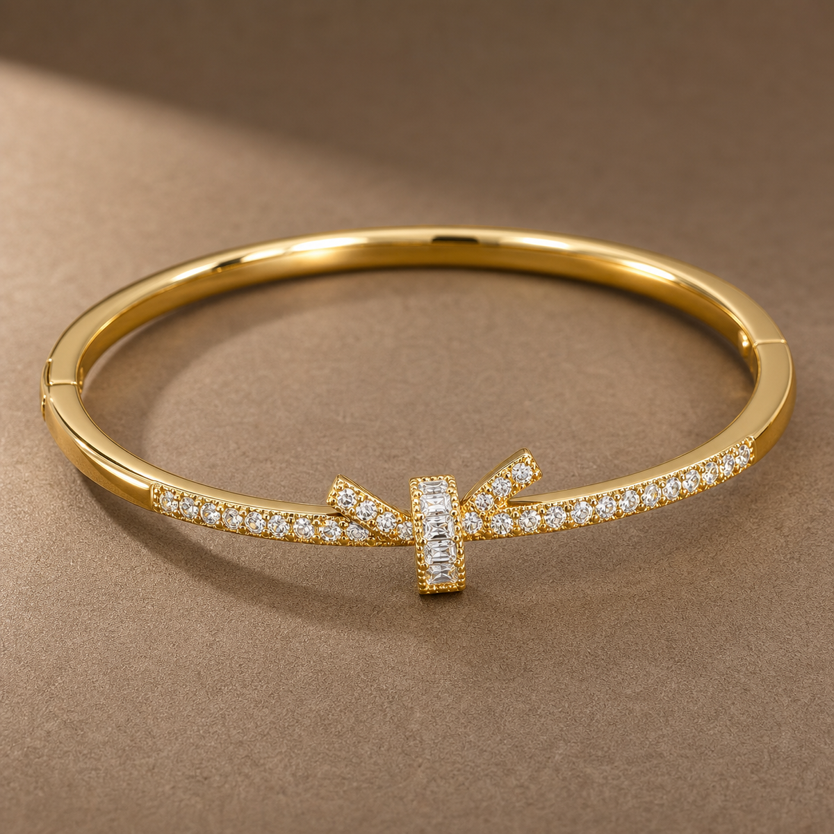 Gold-tone 316L stainless steel bangle with a crystal-set band and a baguette-stone T-bar centre, on a flat surface