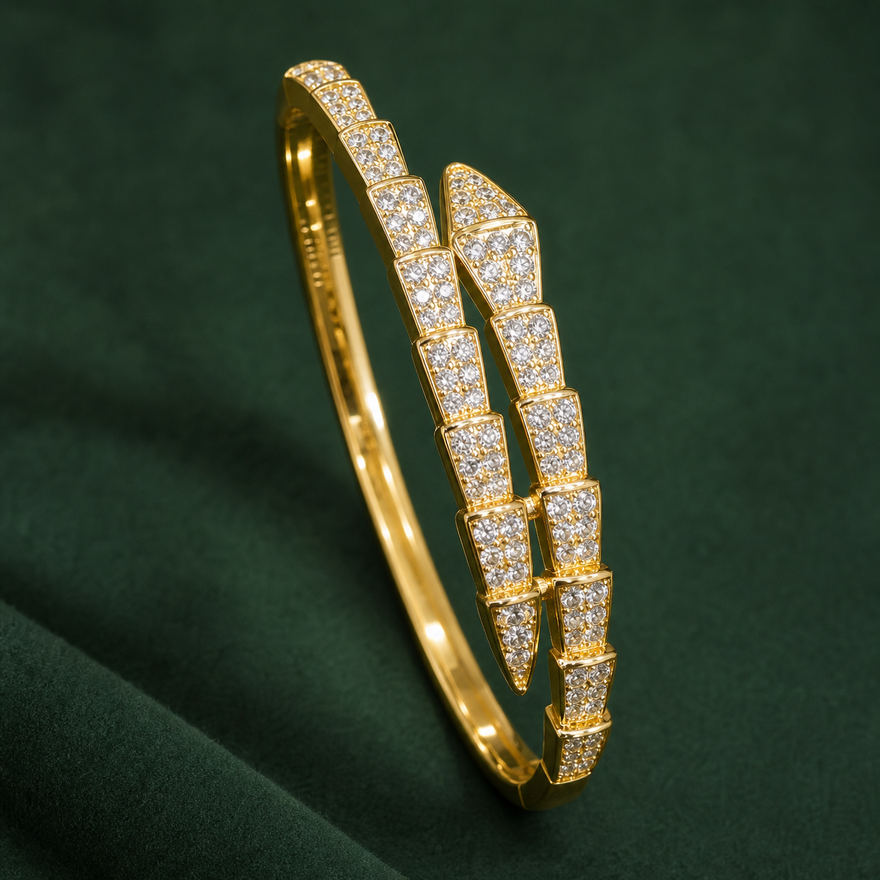 Gold-tone 316L stainless steel kada bracelet with a serpent-scale band set with clear stones, shown on a dark green backdrop