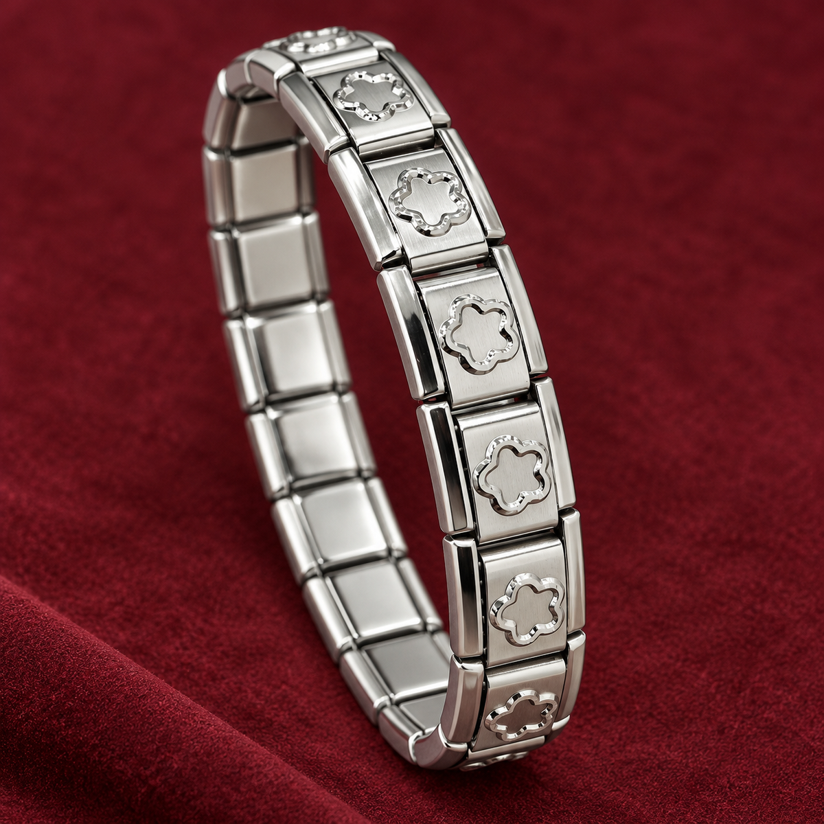 Silver-tone 304 stainless steel stretch bracelet with square links and cut-out flower motifs, lying on a dark red fabric