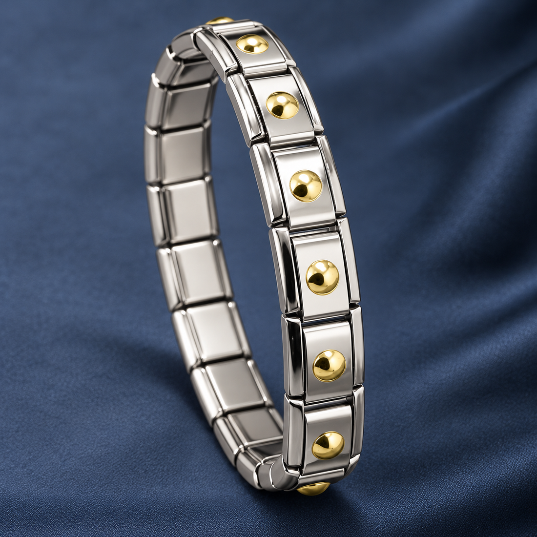 Two-tone stainless steel 304 link bracelet with gold-tone dome studs on each link, lying in a curved loop on a navy fabric background