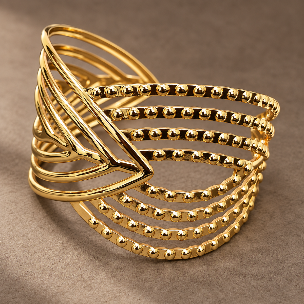 Gold-tone 304 stainless steel cuff bracelet with stacked bands of beaded wire and a sculpted geometric front, shown on a neutral background