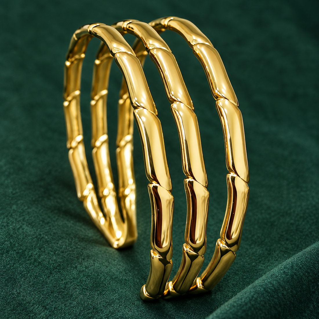 Gold-tone 304 stainless steel bangles with a segmented bamboo-joint design, set of three, shown displayed on a green velvet surface