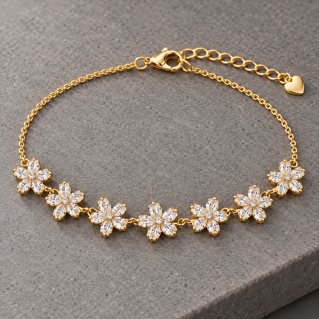 Gold-tone 316L stainless steel chain bracelet with seven crystal-set flower motifs and a heart charm, laid flat