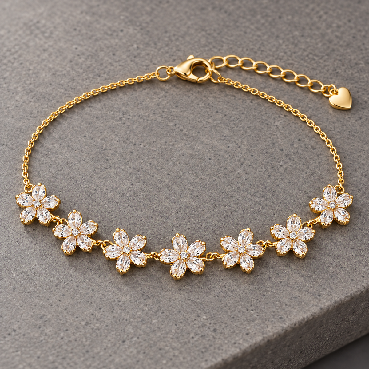 Gold-tone 316L stainless steel chain bracelet with seven crystal-set flower motifs and a heart charm, laid flat