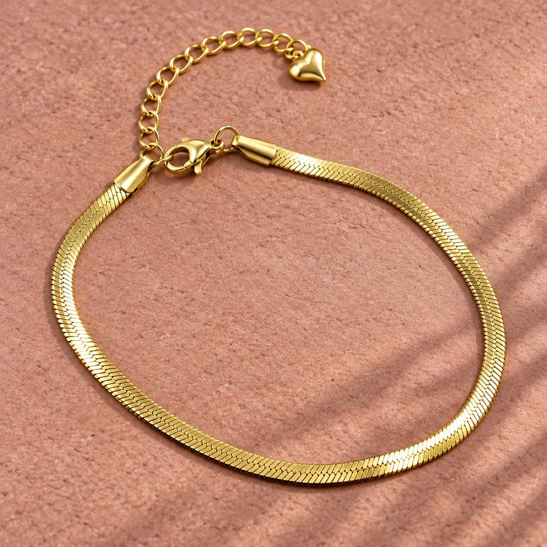 Gold-tone 304 stainless steel herringbone chain bracelet with a lobster clasp, extender chain and small heart charm, laid flat