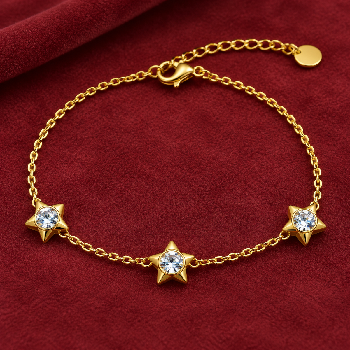 Gold-tone 316L stainless steel chain bracelet with three star motifs each set with a clear round stone, on a red velvet display