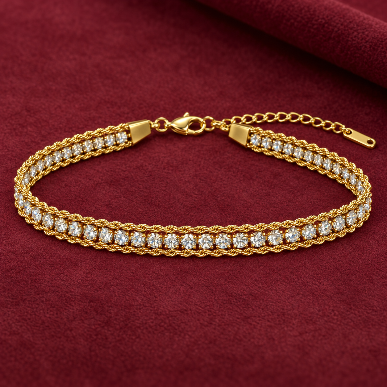 Gold-tone 316L stainless steel bracelet with a rope-twist band and a row of clear crystals in claw settings, laid flat on a maroon cloth