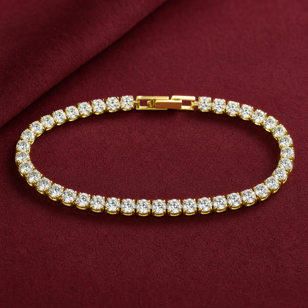 Gold-tone brass tennis bracelet with a row of round clear stones in claw settings and a box clasp, laid flat on a deep red cloth