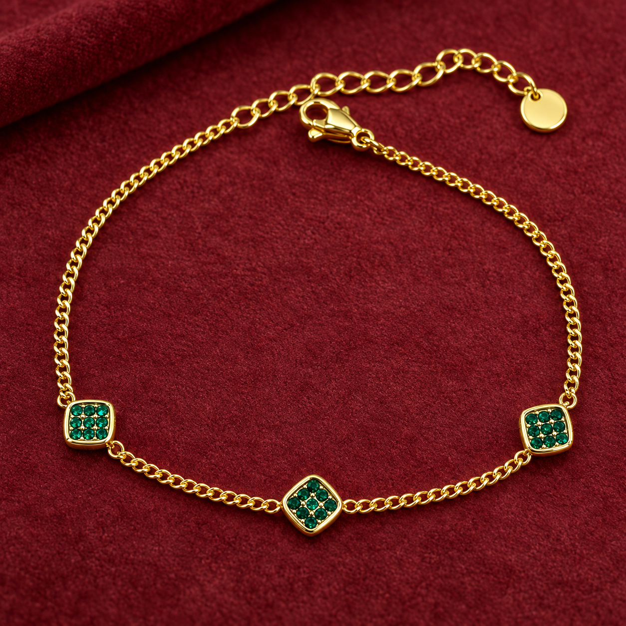 Gold-tone 316L chain bracelet with three square green stone-set motifs on a curb chain, lobster clasp and extender, laid flat