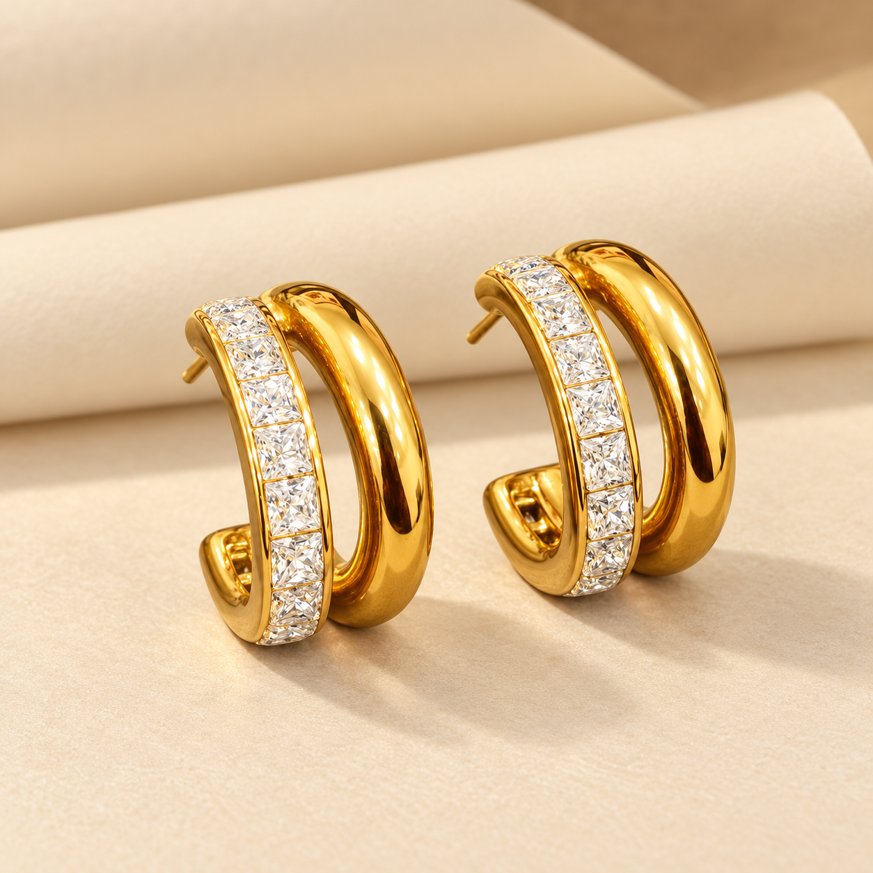 Gold-tone 316L stainless steel double-hoop earrings with a row of square clear crystals on the outer hoop and a smooth inner hoop, shown as a pair