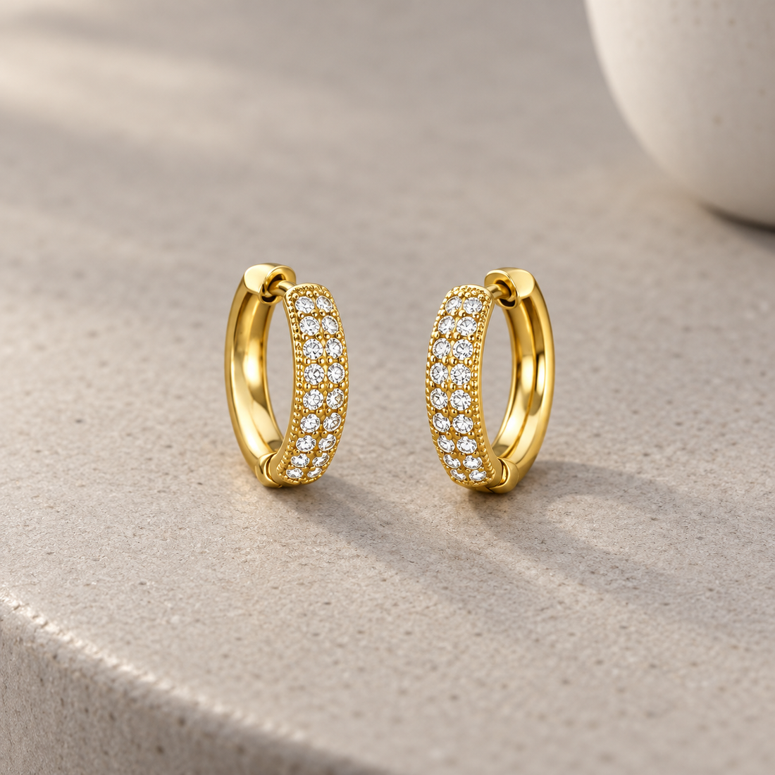 Gold-tone 316L stainless steel huggie hoop earrings, a pair, with rows of small clear stones set across the front of each hoop