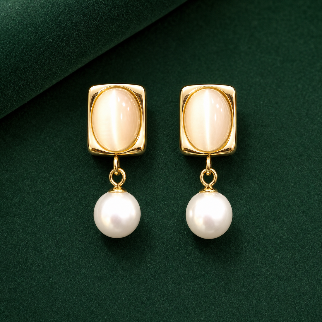 Gold-tone 304 stainless steel drop earrings with a rectangular frame set with a cream cat's-eye stone and a hanging white pearl, shown as a pair