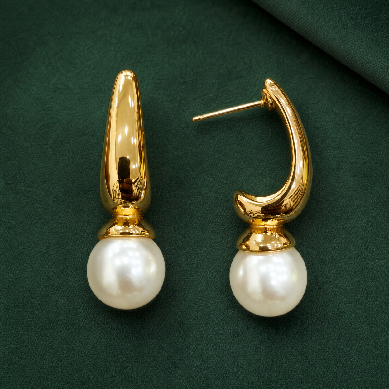 Gold-tone 304 stainless steel drop earrings with a curved tapered hoop and a white pearl bead below, shown as a pair on a green background