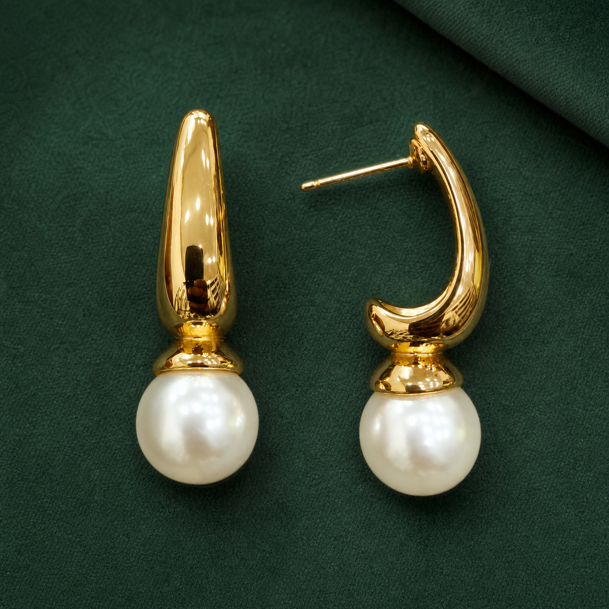 Gold-tone 304 stainless steel drop earrings with a curved tapered hoop and a white pearl bead below, shown as a pair on a green background