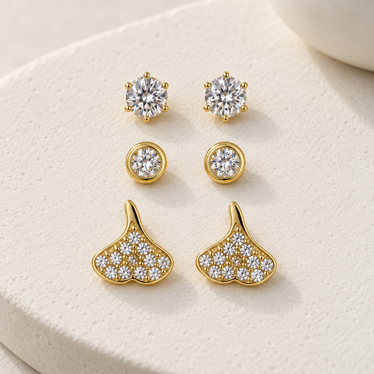 Gold-tone 316L stainless steel stud earrings set of three: round crystal solitaires, bezel-set crystals and ginkgo-leaf studs with crystal pave