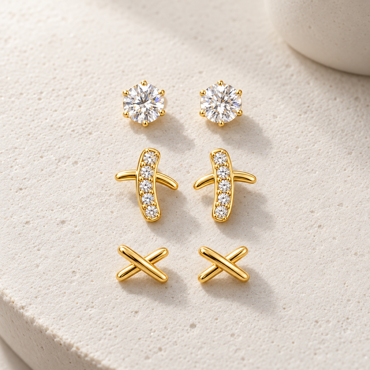 Gold-tone 316L stainless steel earrings set of three: round crystal studs, crystal-set bar studs, and plain crossed studs