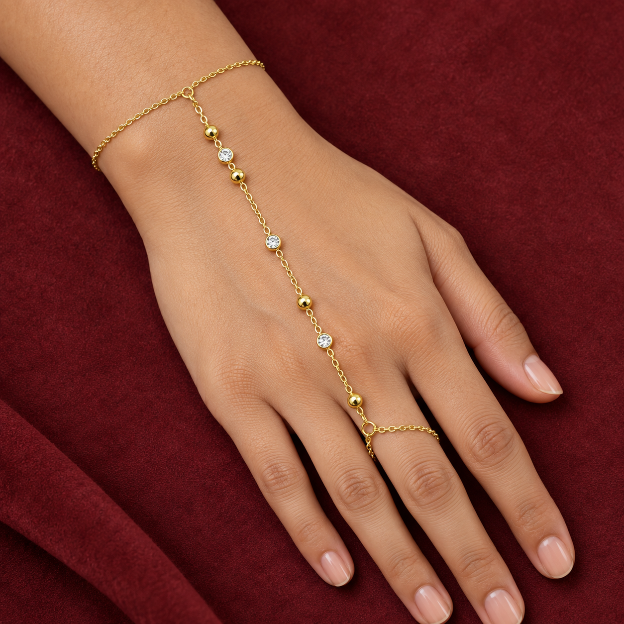 Gold-tone 304 stainless steel hand chain with alternating gold beads and clear round stones, linking a wrist bracelet to a finger ring, worn on a hand