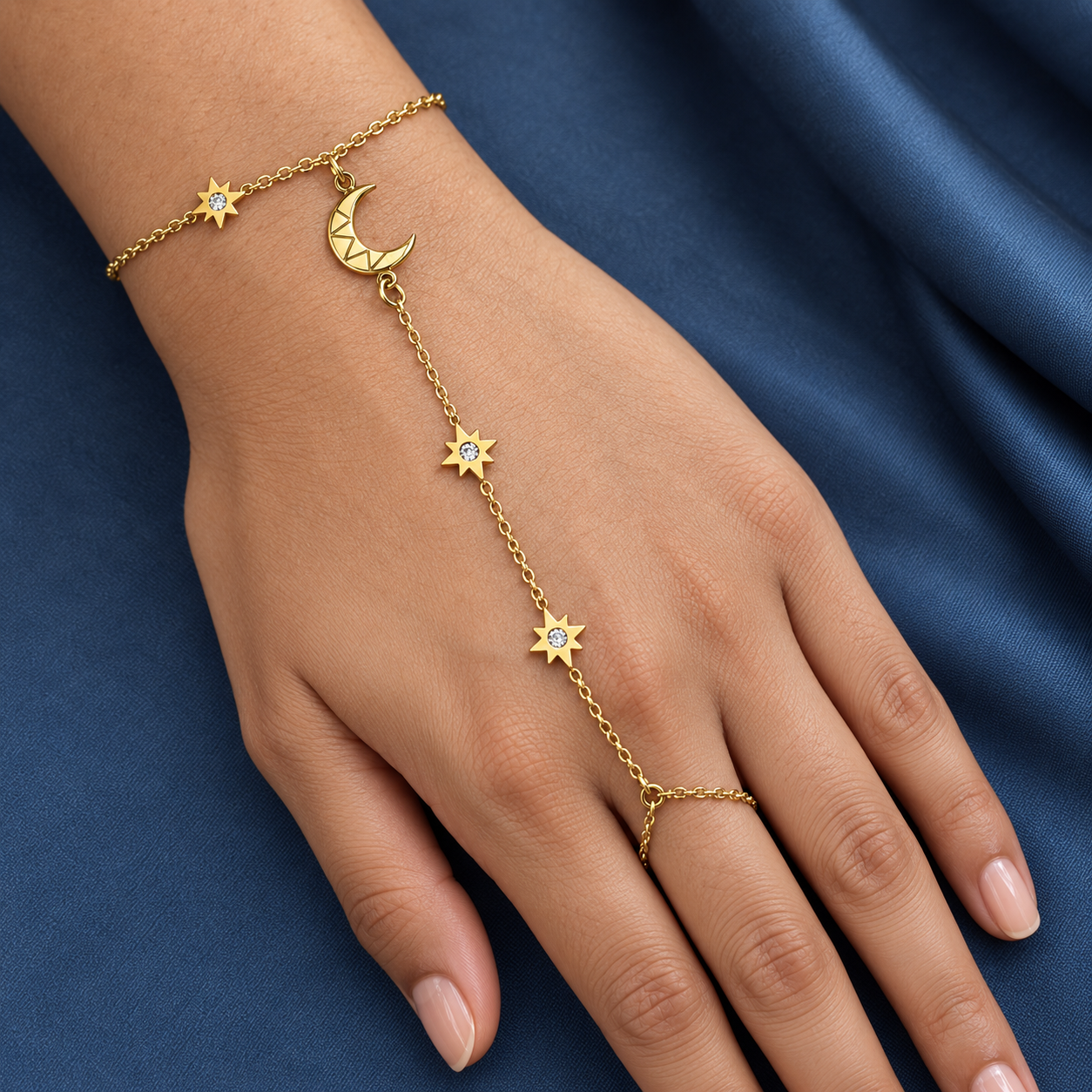 Gold-tone 304 stainless steel hand chain with a crescent moon and star charms set with clear stones, linked to a finger ring, worn on a hand