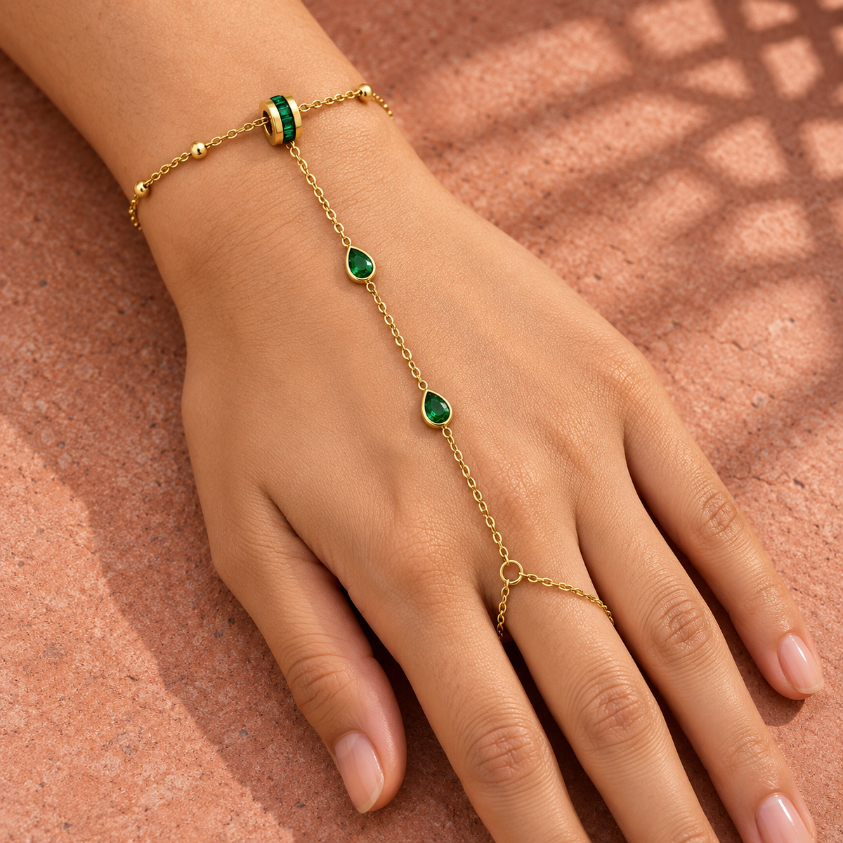 Gold-tone 304 stainless steel hand chain bracelet with green pear-cut stones and a ring link on the middle finger, worn on a hand