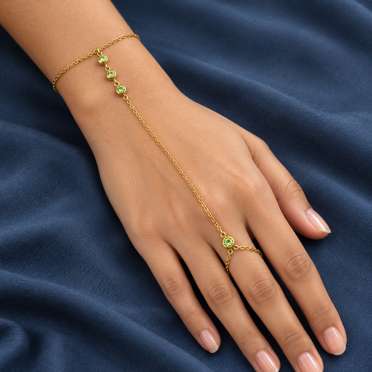 Gold-tone 304 stainless steel hand chain bracelet with a finger ring and three green stones on the back of the hand, worn on a hand