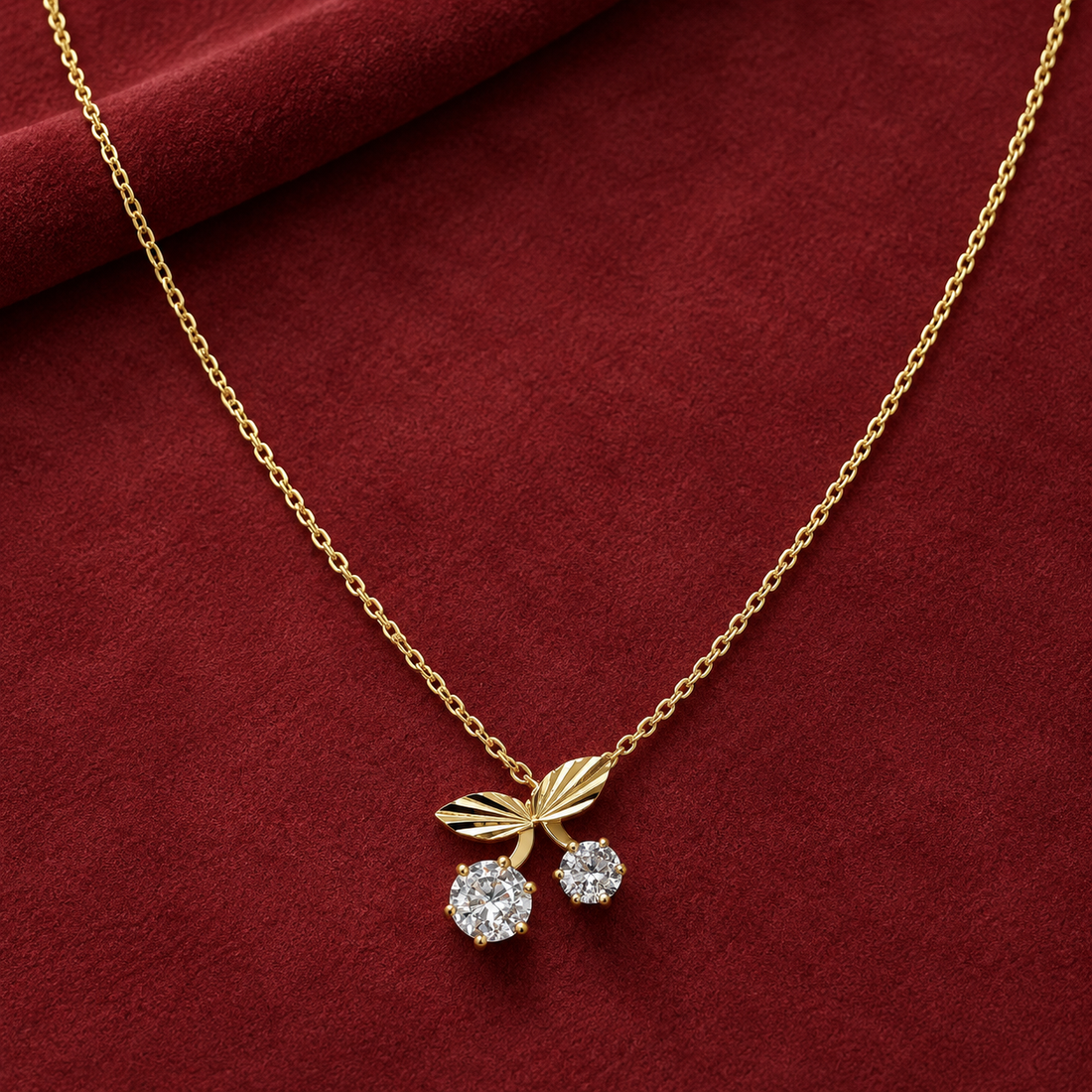 Gold-tone 304 stainless steel necklace with a cherry pendant of two clear stones set in claws and two leaves, on a fine cable chain