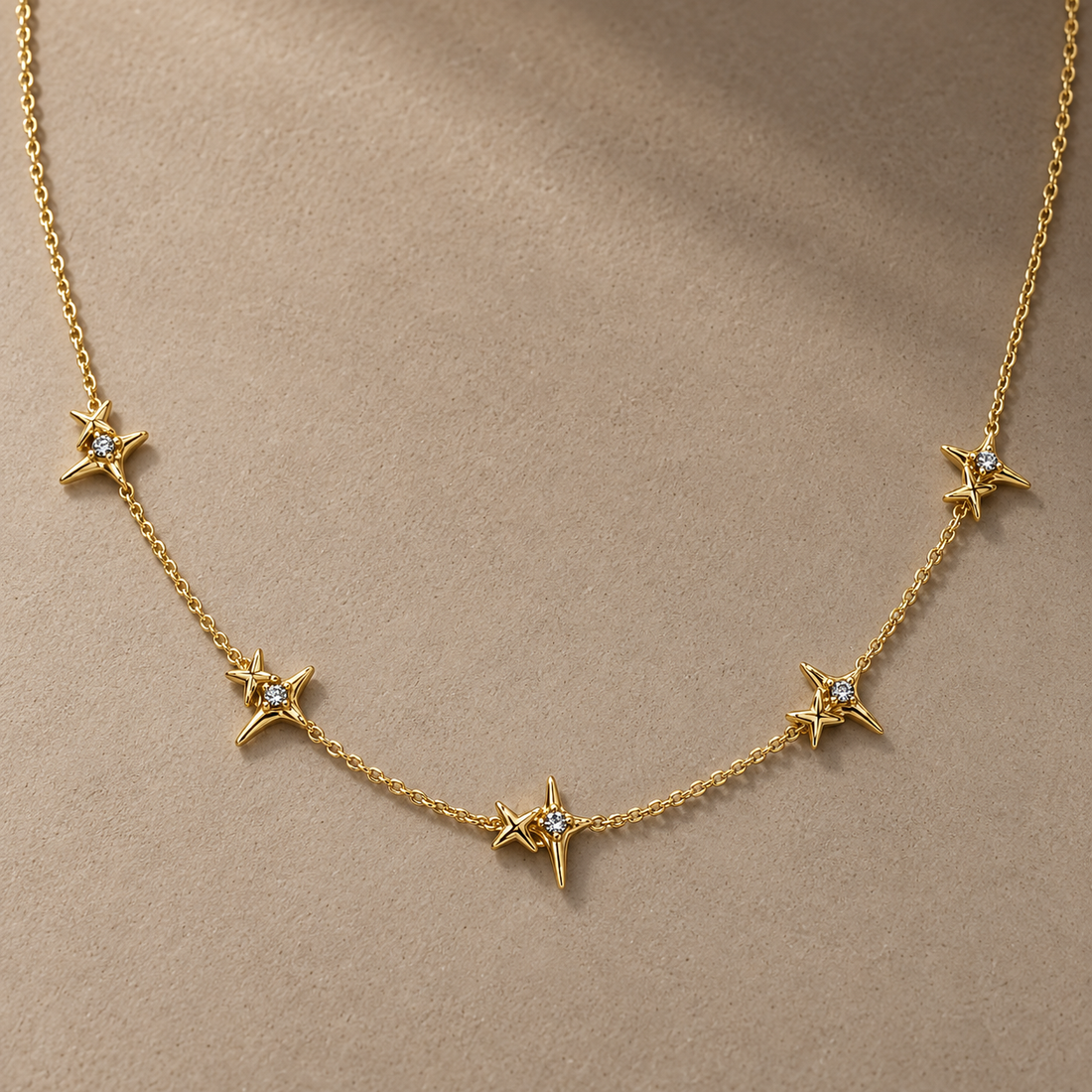 Gold-tone 316L stainless steel necklace with five four-point star motifs each set with a clear stone, spaced along a fine cable chain