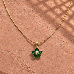 Gold-tone 316L stainless steel pendant necklace with a five-stone green flower pendant on a snake chain, laid on a stone surface