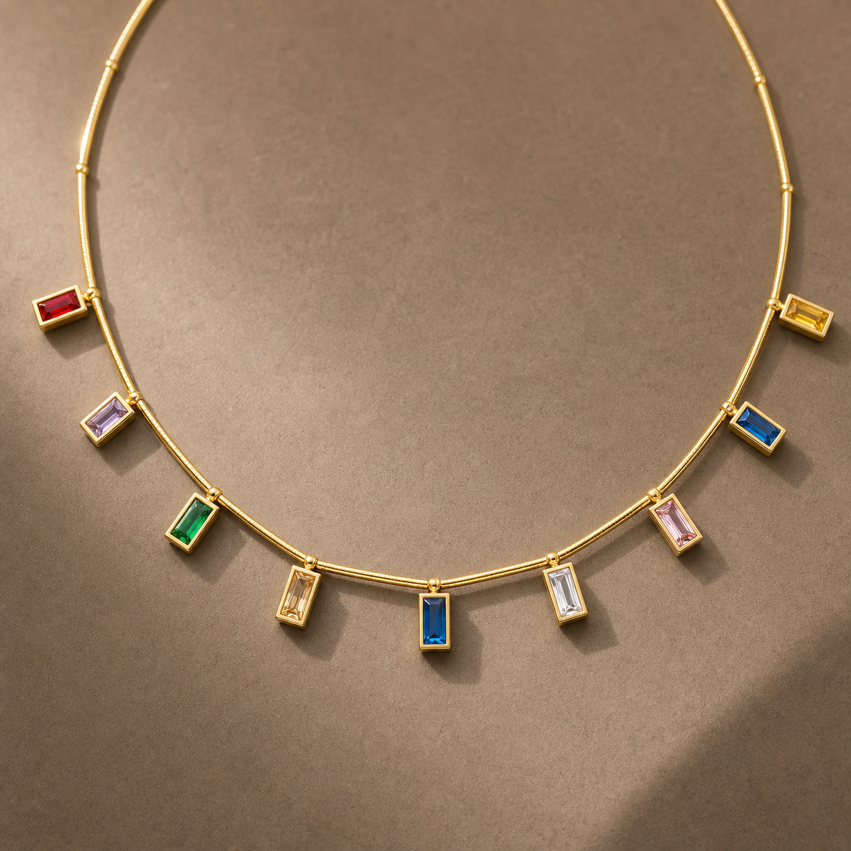Gold-tone 304 stainless steel necklace with a thin rigid bar chain and nine bezel-set rectangular stones in red, green, blue, pink, yellow and white