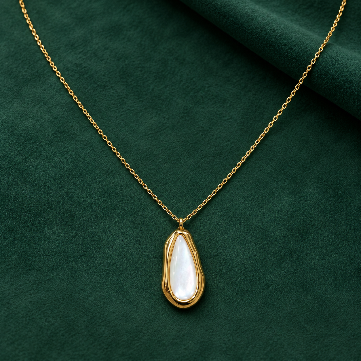Gold-tone 316L stainless steel necklace with a teardrop mother-of-pearl pendant in a wavy gold-tone bezel on a fine cable chain