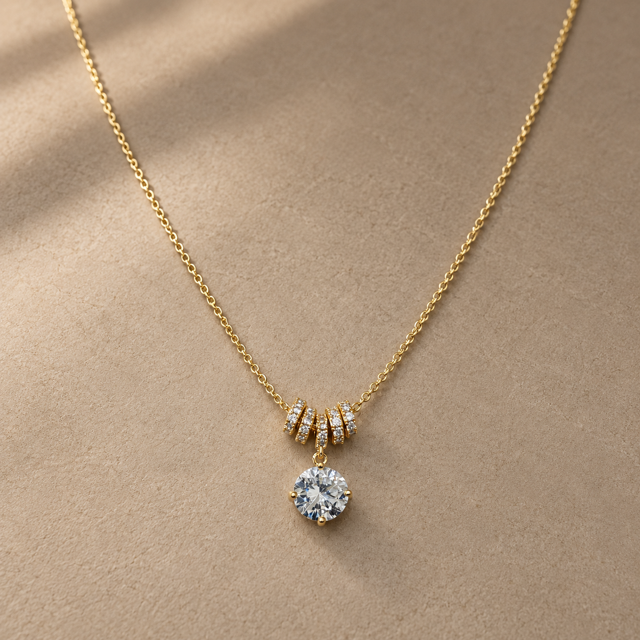 Gold-tone 316L stainless steel necklace with a round crystal pendant and four pavé-set rings on a fine chain