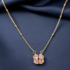 Gold-tone 304 stainless steel necklace with a four-leaf clover pendant of pink heart-cut stones on a satellite bead chain, shown laid on navy fabric