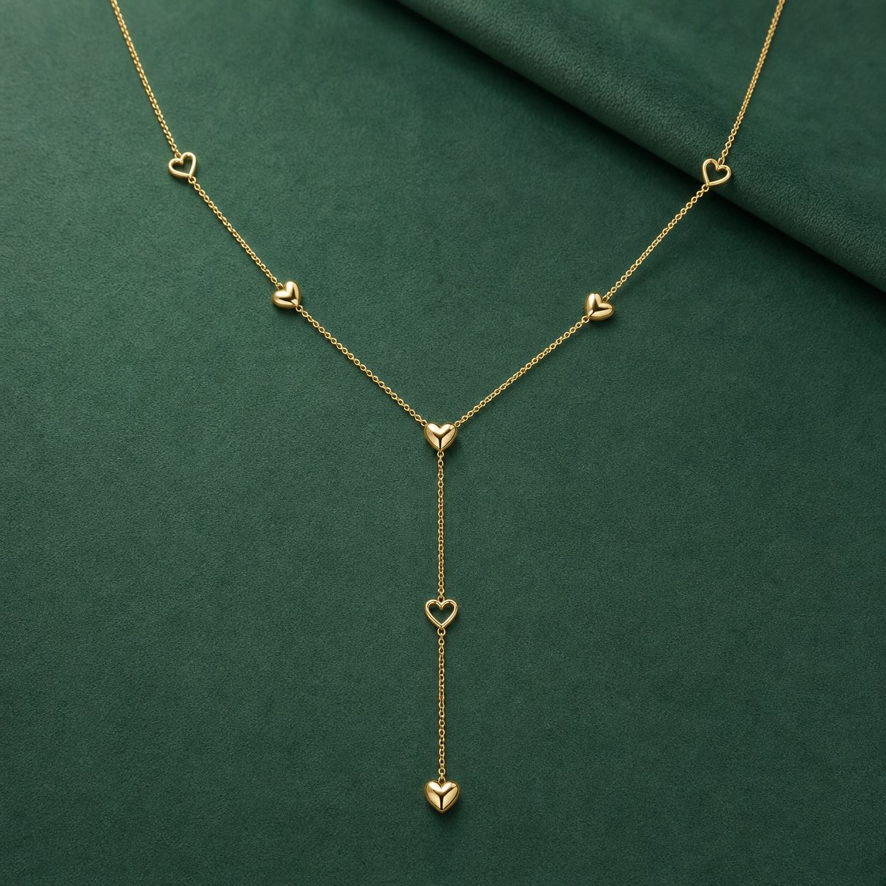 Gold-tone 316L stainless steel lariat necklace with a fine chain and small heart motifs, one pendant heart hanging on a drop chain