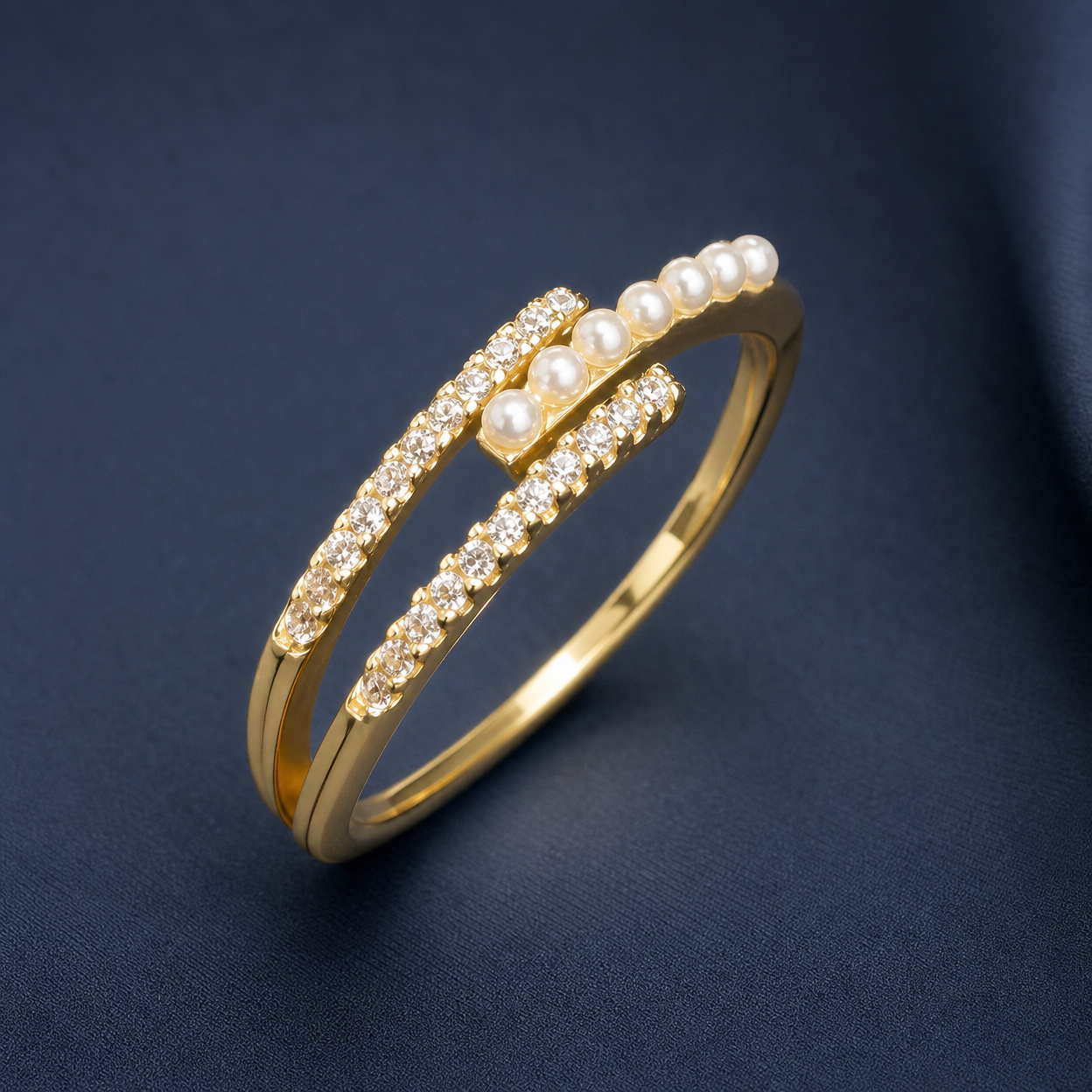 Gold-tone 316L stainless steel open ring with a pave crystal band and a row of small pearls across the top, shown on a dark fabric