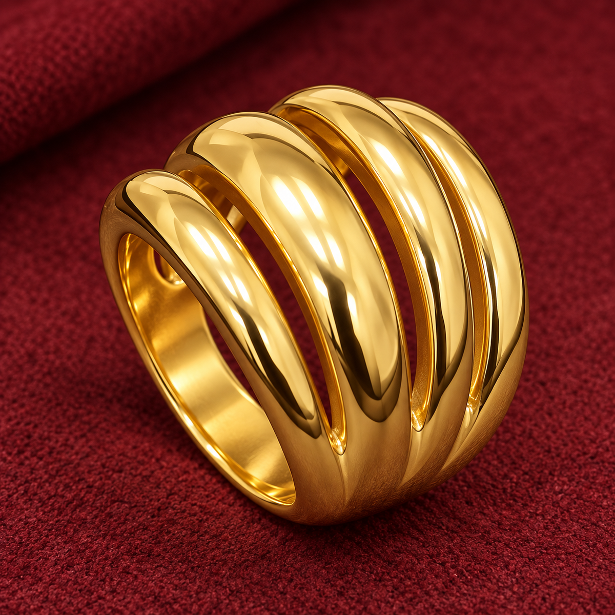 Gold-tone 316L stainless steel wide ring with four stacked polished domed bands, shown on a red fabric surface